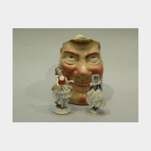 Two German Porcelain Crinoline Figures and a Sarreguemines Ceramic Character Jug.
