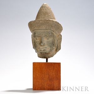 Carved Stone Head of a Deity, Khmer, Angkor period-style, wearing a flared headdress with a cone-shaped brim, decorated with geometric
