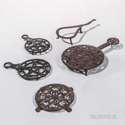 One Wrought Iron and Four Cast Iron Trivets