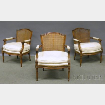 Set of Three Louis XVI-style Upholstered and Caned Carved Walnut Fauteuils. 