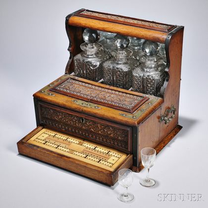 Carved Oak Liquor Set, England, late 19th century, comprising three square cut glass decanters with stoppers, above two hinged lids ope