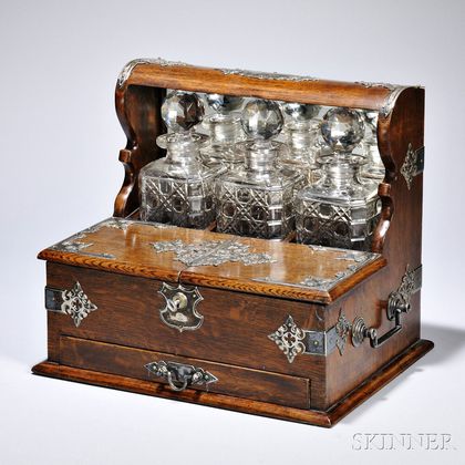 Silver-mounted Oak Liquor Set, England, late 19th century, comprised of three glass decanters with stoppers, above two hinged lids whic