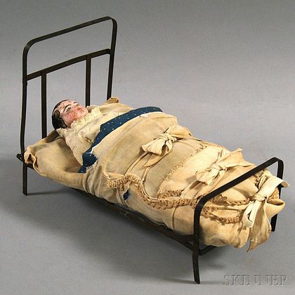 Carved and Painted Wood Doll in an Iron Bed